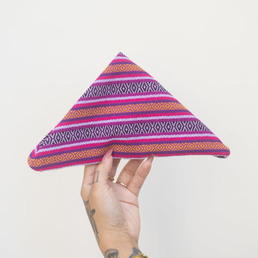 Hand holding a colorful triangular fabric item against a white background